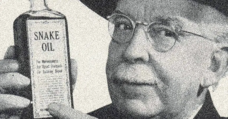 A black and white photo of an older man with glasses and mustache, looking at the camera and holding up and pointing to a bottle of Snake Oil.